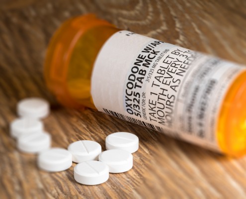 Tiltshift effect of prescription bottle for Oxycodone tablets and pills on wooden table for opioid epidemic illustration