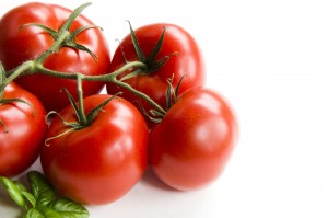 Cluster of five tomatoes on a white background with basil.