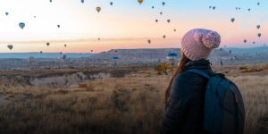 women looking over canyon with hot air balloons